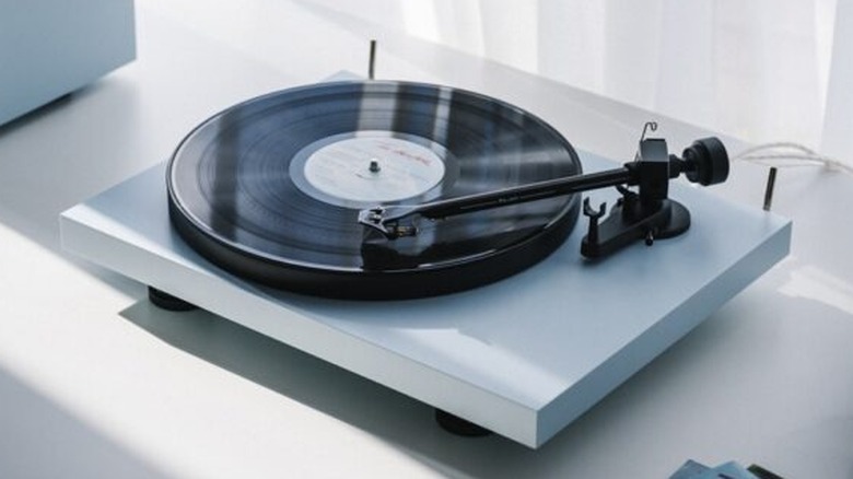 A minimalist white Pro-Ject turntable with a spinning vinyl record.