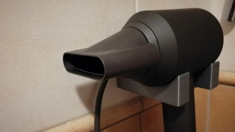 A Dyson hair dryer securely held by a custom-designed 3D printed wall rack.