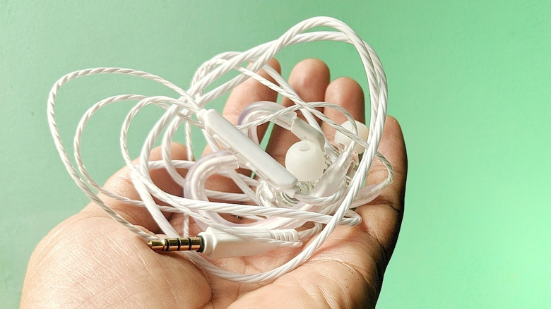 A pair of white wired earbuds inextricably tangled in a messy knot.