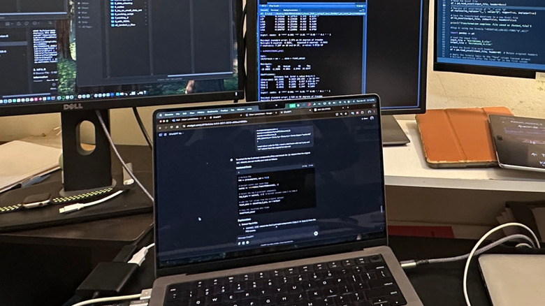 A MacBook connected to two large external displays showing an extended desktop.