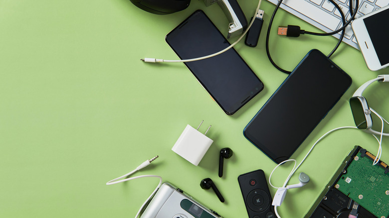 A curated collection of electronic gadgets including a smartphone, headphones, and peripherals on a green surface.