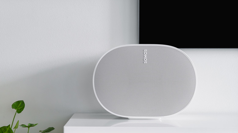 A portable cylindrical Bluetooth speaker placed directly under a television screen.