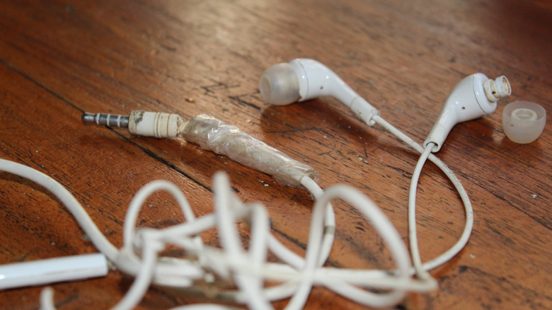 Close-up of a wired earbud cable with visible fraying and damage near the connector jack.