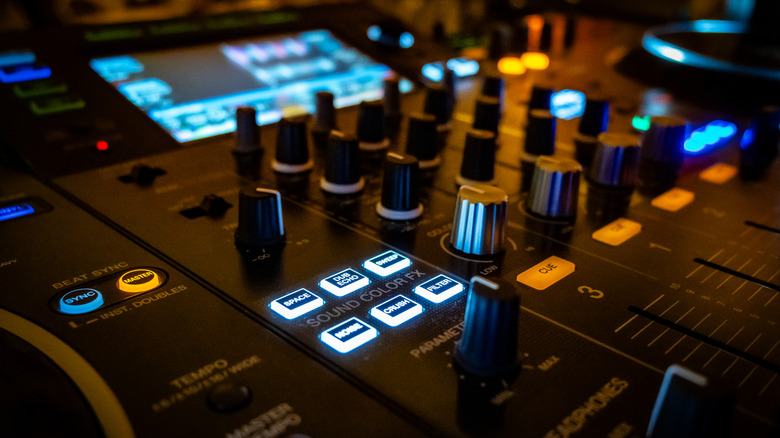 Close up of an advanced digital audio mixer showing faders and signal lights.