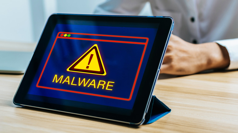 Tablet screen displaying a red malware alert and security warning.