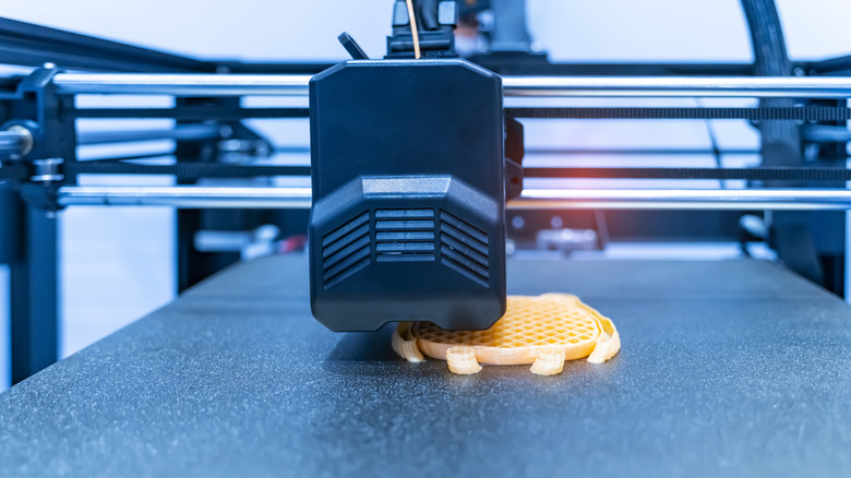 A detailed view of a 3D printer mid-print, showing the layer-by-layer construction of a part.
