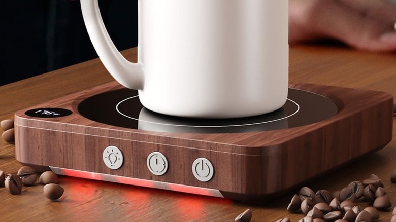 A white mug resting on a House Gem Mug Warmer with an orange-red glow.