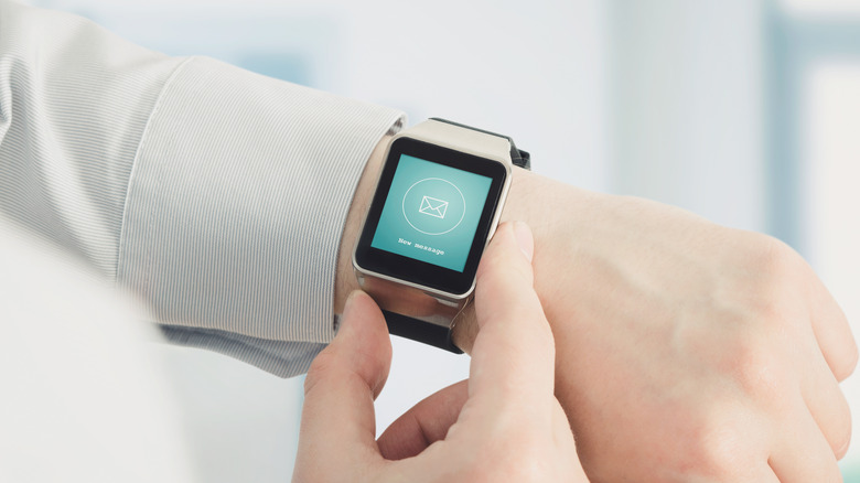 A smartwatch displaying a prominent email notification icon on its face.