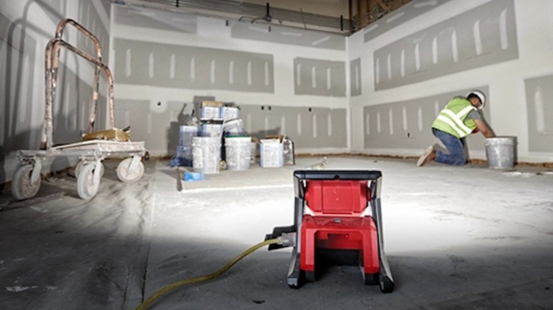 The Milwaukee M18 Rover Flood Light providing bright, white light in a dark work environment.
