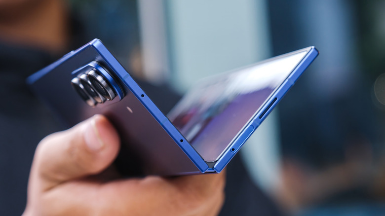A Galaxy Z Fold 7 being held in a partially folded position, showing the sleek silver hinge and thin display panels.