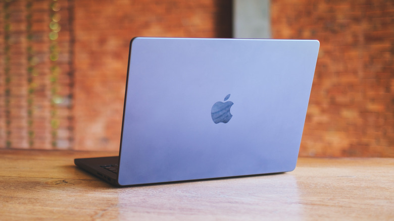 An Apple MacBook Pro laptop open on a wooden table in a professional setting.