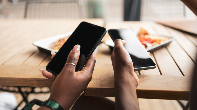 Close up of two people tapping phones together to share contact information.