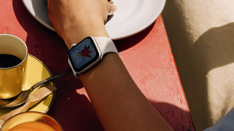 An Apple Watch SE 3 worn on a person's wrist in a shaded outdoor setting.