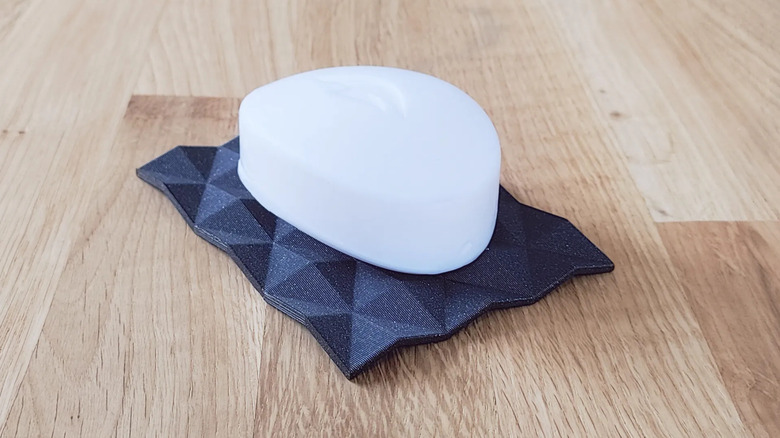 A bar of soap resting on a 3D printed soap dish designed with built-in drainage slots.