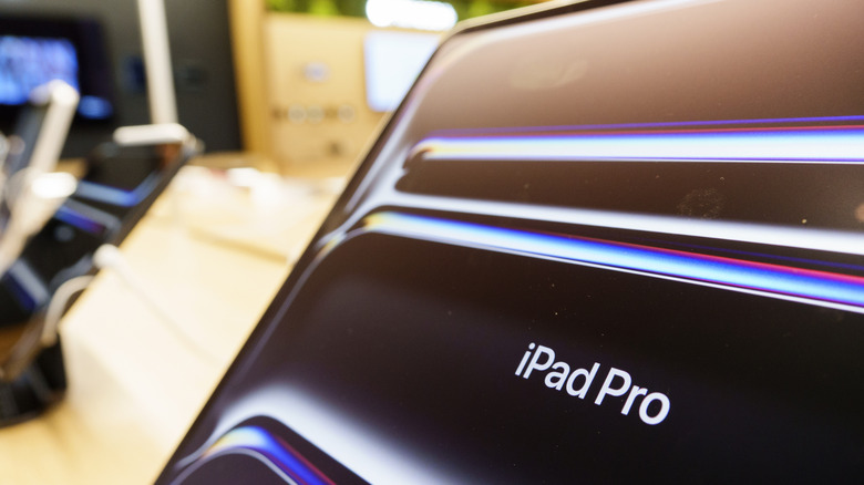 An iPad Pro on a retail display stand inside a bright electronics store.