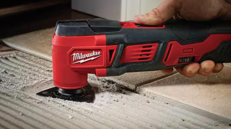 A person using a Milwaukee M18 Oscillating Multi-Tool to make a precise cut in wood.