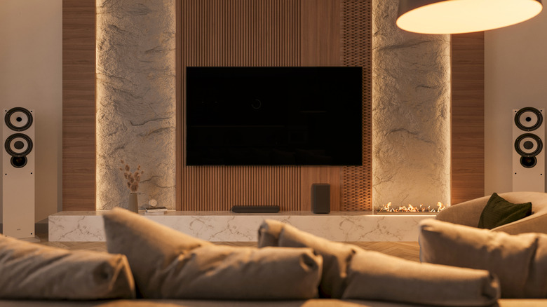 A modern living room featuring high-fidelity floor-standing speakers and a large wall-mounted screen.