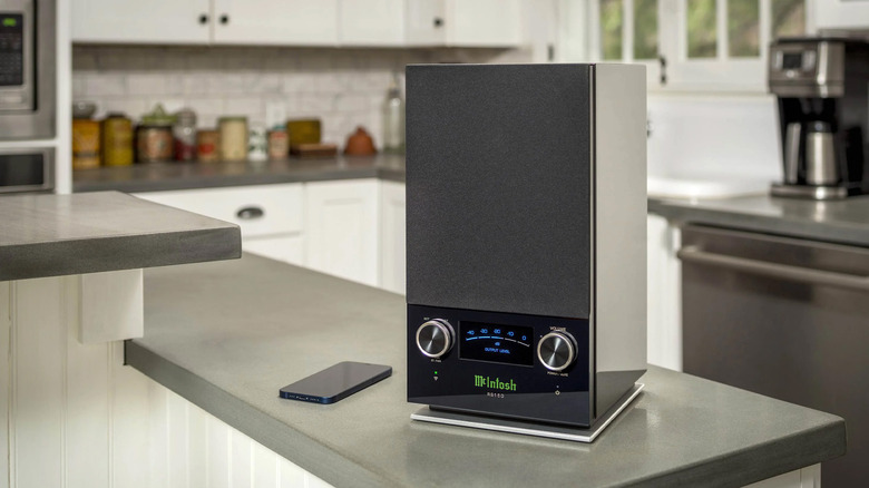 A McIntosh RS150 speaker with its signature glowing blue meter sitting on a kitchen bar.
