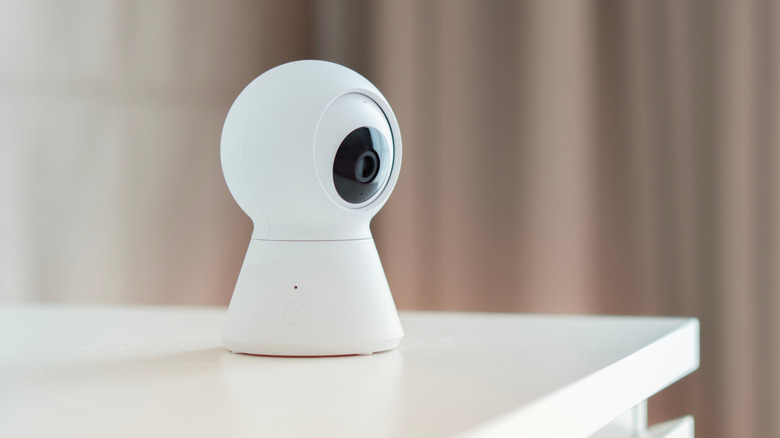 A white indoor security camera resting on a clean white surface.