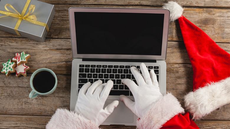A person in a Santa Claus suit using a laptop for holiday shopping.
