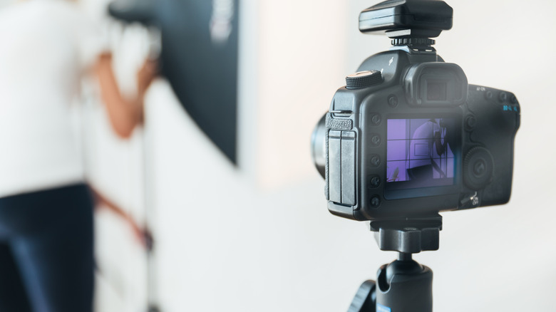 Photography studio setup with a DSLR camera mounted on a tripod and professional lighting.