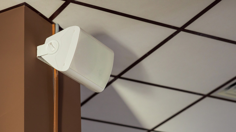 A sleek white wall-mounted speaker positioned near a modern ceiling.