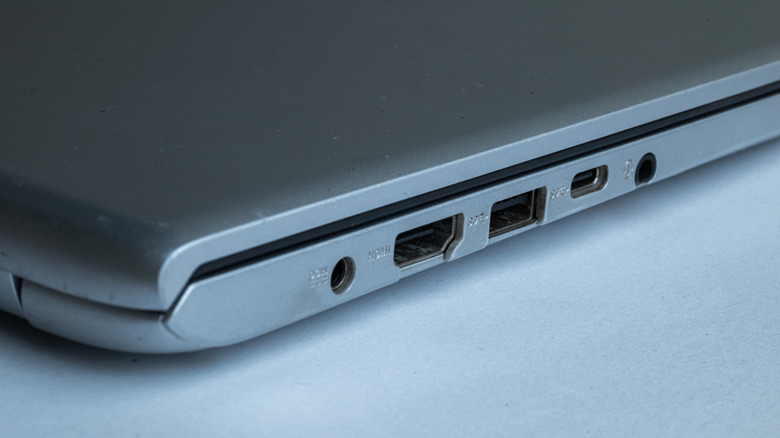 Side view of a silver laptop highlighting the circular 3.5mm headphone jack port and adjacent USB connections.