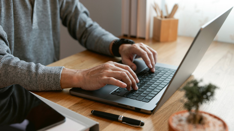 A person working at a desk with a laptop and office supplies.