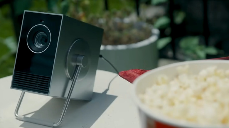 The LG CineBeam Q positioned on an outdoor wooden table during a picnic setup.