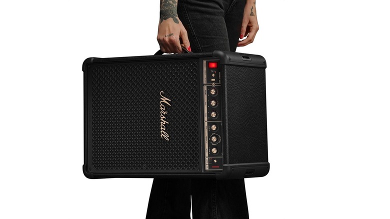 A person carrying the Marshall Bromley 450 using its integrated side strap.