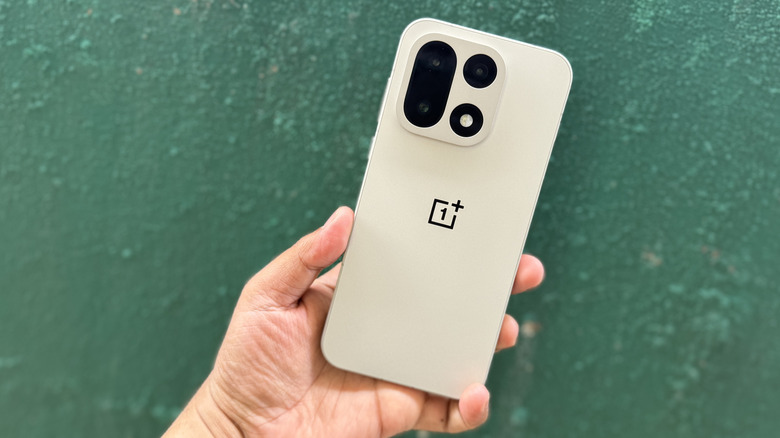 Close-up of the textured rear shell of the OnePlus 15 in Sand Storm color.