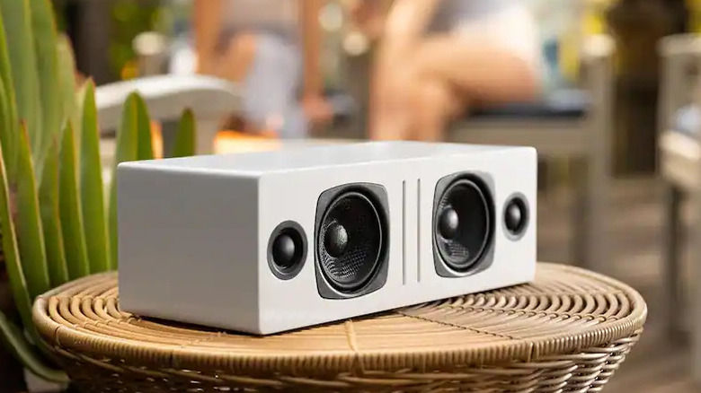 An Audioengine B2 wireless speaker placed on a wooden outdoor surface.