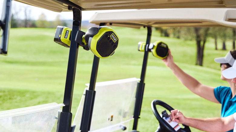 A green Ryobi Verse Clamp Speaker attached to the frame of a golf cart.