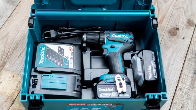A Makita electric drill kit in a box with its accompanying battery and rapid charger.