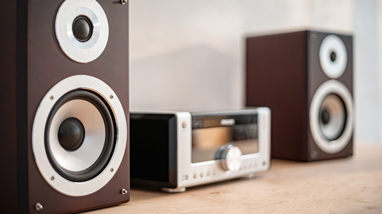 Minimalist bookshelf speakers and an audio receiver on a warm wooden surface.