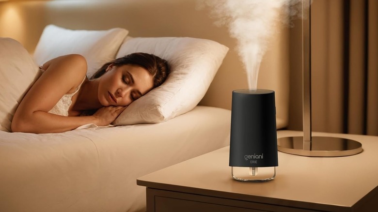 A Geniani Erie humidifier providing mist on a bedside table while a person sleeps nearby.