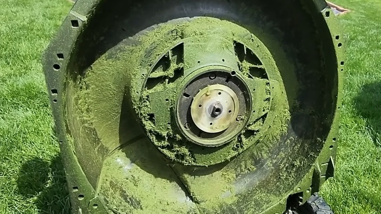 The underside of an Ego mower deck showing accumulated grass clippings and mulch.