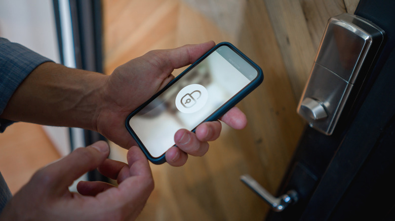 A person using a smartphone with a lock icon to unlock a door via NFC.