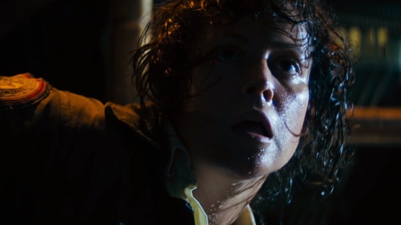 Ellen Ripley looking distressed in the dark industrial setting of the Nostromo.
