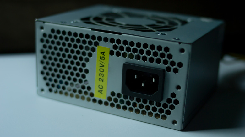 An older, unbranded power supply unit showing basic construction and cooling fan.