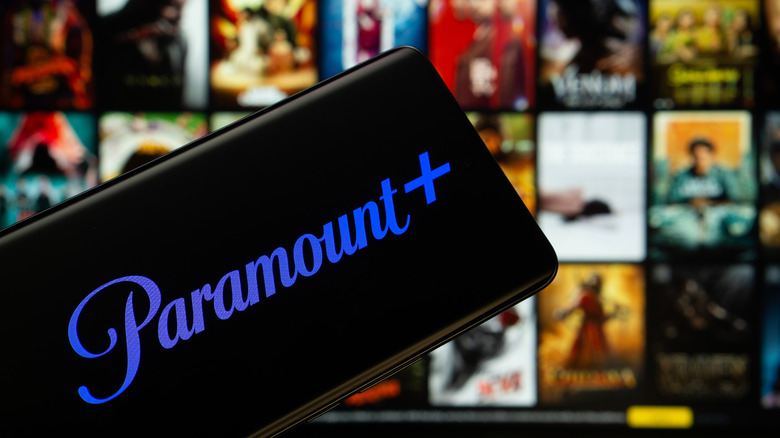A close-up of the Paramount+ logo on a mobile screen with blurred video content in the background.