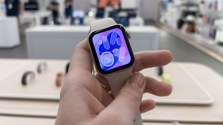 Close-up of the Apple Watch SE 3 being held in a bright retail setting.