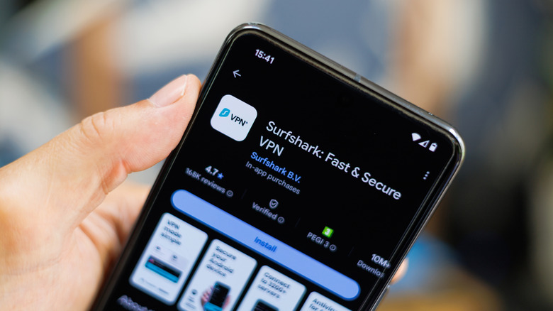 A person holding a phone showing the Surfshark VPN download page in the Google Play Store.
