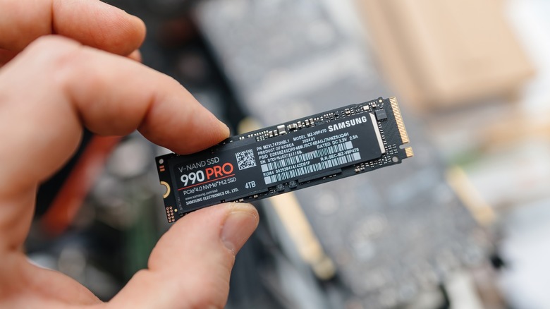 A person holding a Samsung 990 PRO NVMe SSD between their fingers.