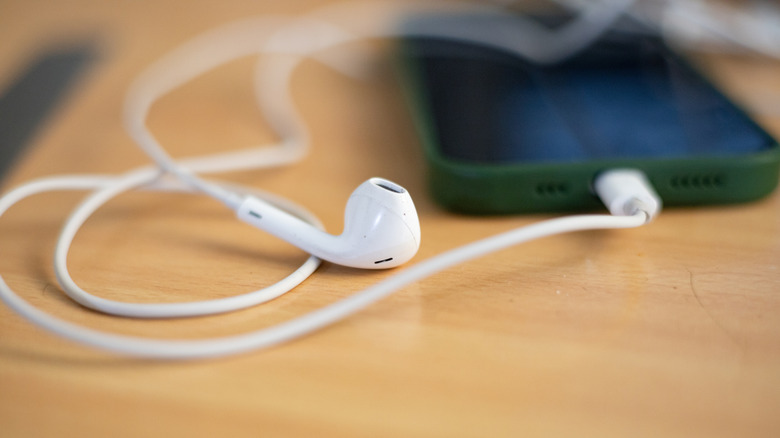 White wired consumer-grade earbuds connected to a smartphone.
