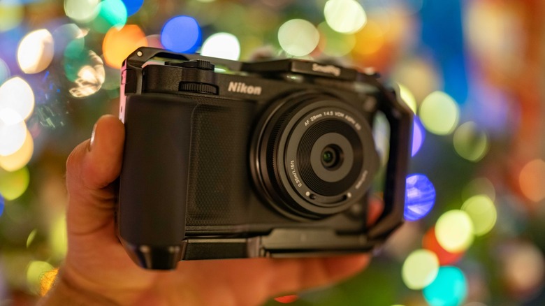 Nikon Zr held in a hand with a Viltrox 28mm lens against a backdrop of bokeh lights.
