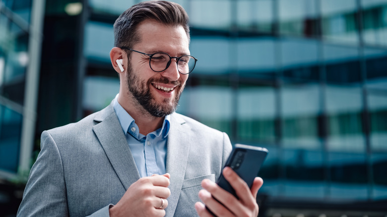 A professional man using wireless earbuds for a phone call while looking focused.