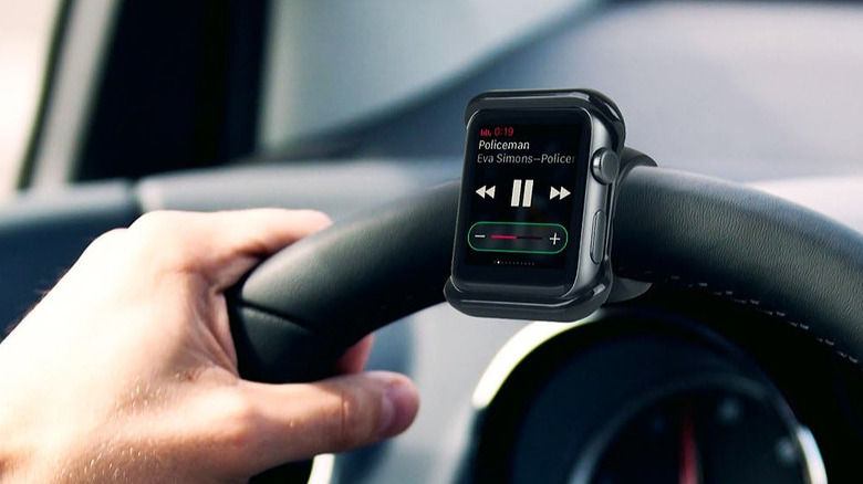 A smartwatch mounted to the steering wheel of a vehicle.