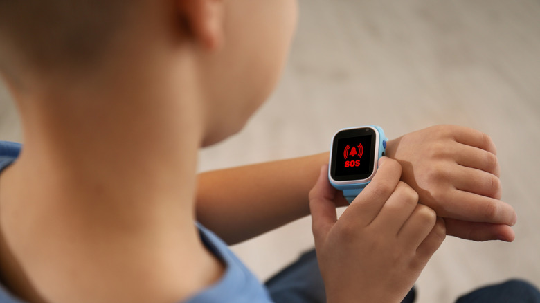 A child pressing an emergency SOS button on their digital smartwatch.