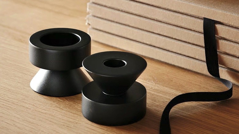A pair of Stockholm 2025 metal candle holders with a modern sculptural design on a tabletop.